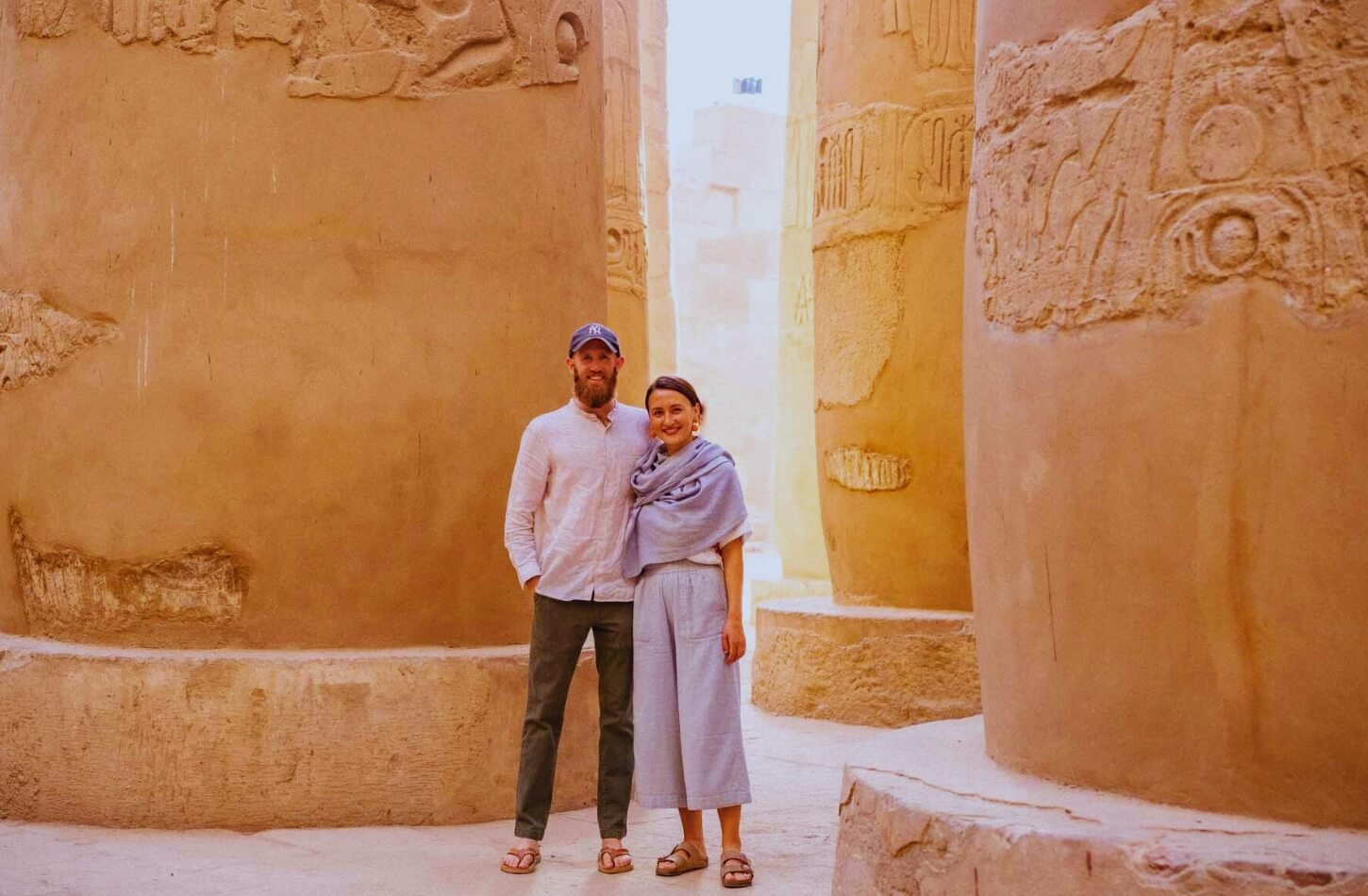 a couple explores an ancient egyptian temple dressed in light breathable clothing and sandals perfect for the heat