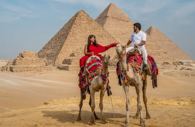 Couple riding camels in breathable outfits at the Giza Pyramids illustrating an Egypt packing list