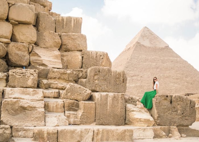 A wonderful picture of a girl sitting on a rock in the pyramid wearing a green skirt
