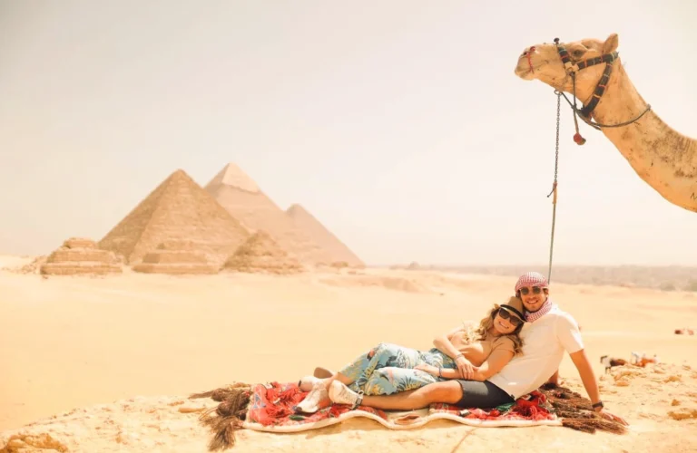 A stunning photo of a honeymoon couple sitting in front of the pyramids