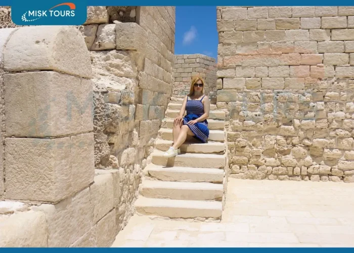 A-blonde-woman-in-a-blue-dress-sitting-on-the-stone-stairs-of-an-ancient-fortress.