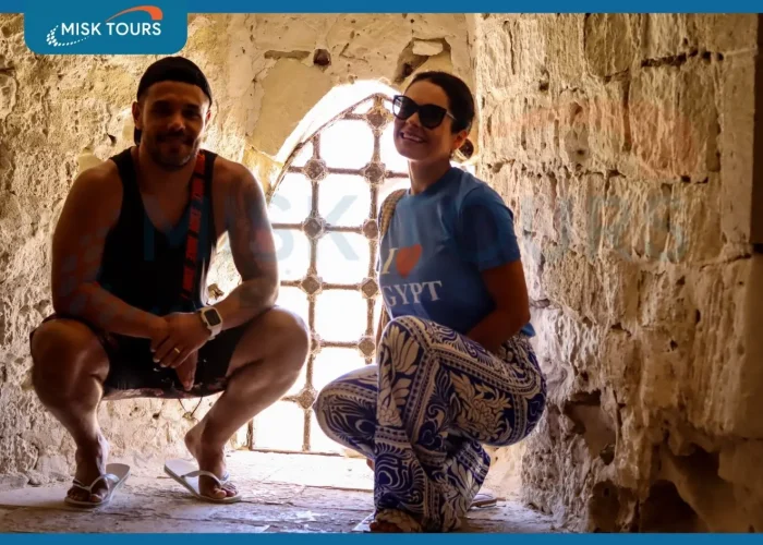 A-smiling-couple-crouching-inside-a-stone-fortress-window-niche-with-the-woman-wearing-an-i-love-egypt-shirt.