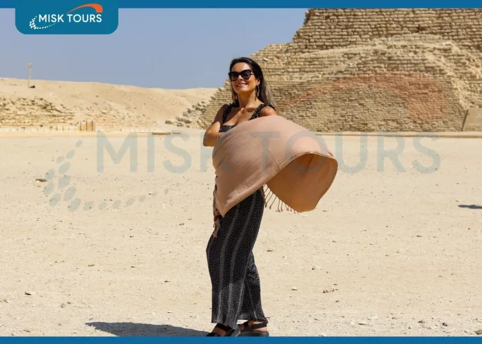 smiling-woman-tourist-holding-flowing-shawl-at-step-pyramid-of-djoser-saqqara.