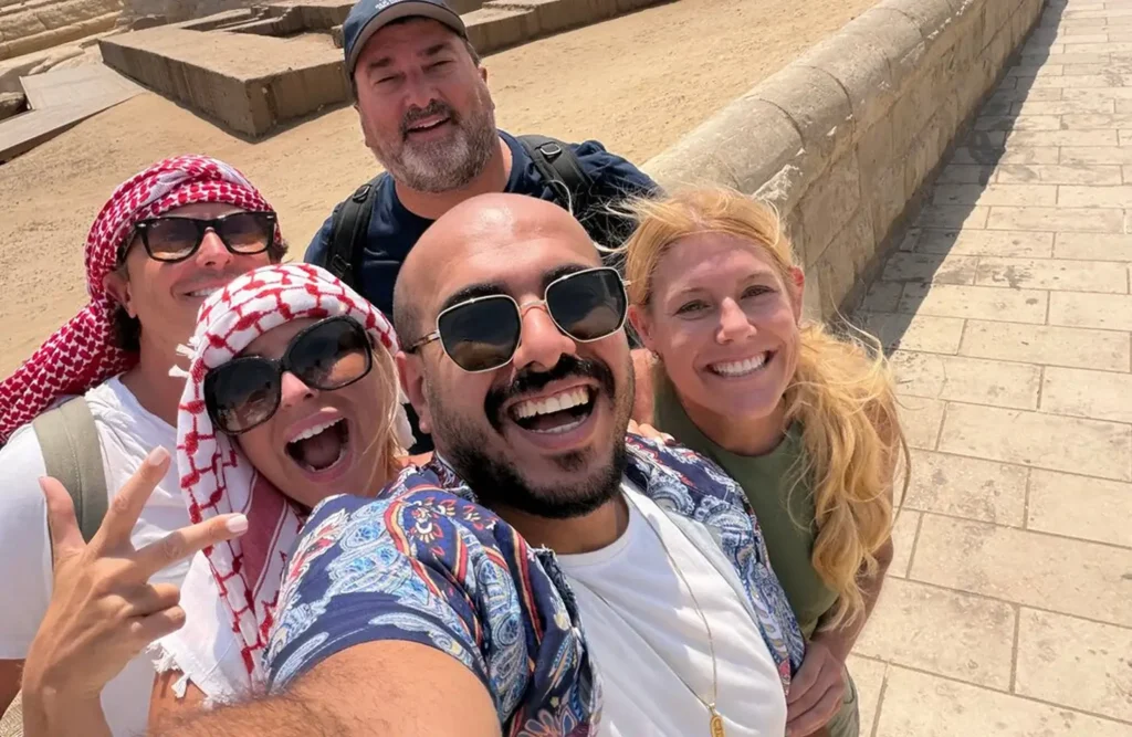 A stunning image of a group of cheerful tourists taking a selfie near ancient egyptian ruins