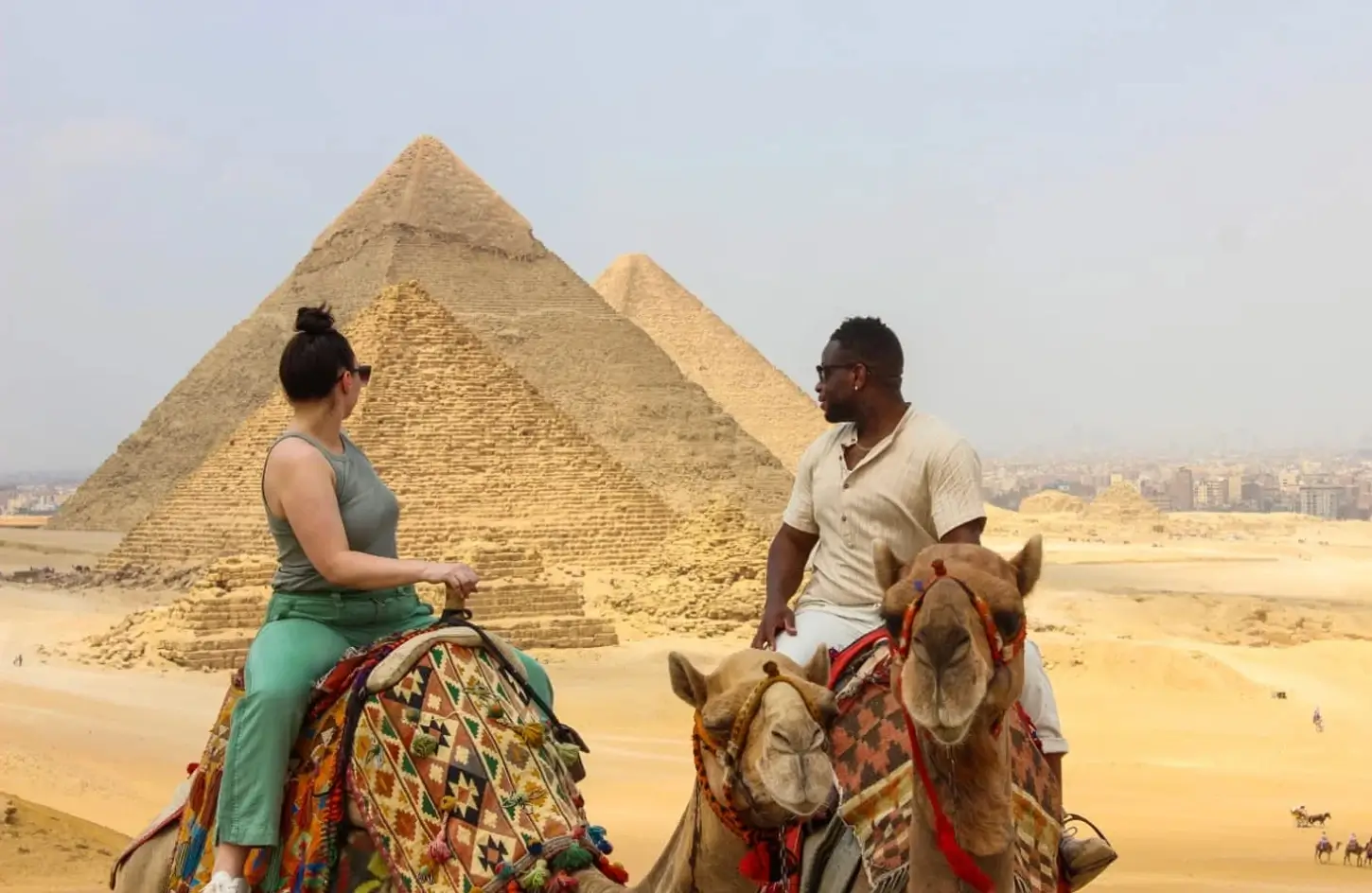 Couple riding camels in front of the Great Pyramid of Giza
