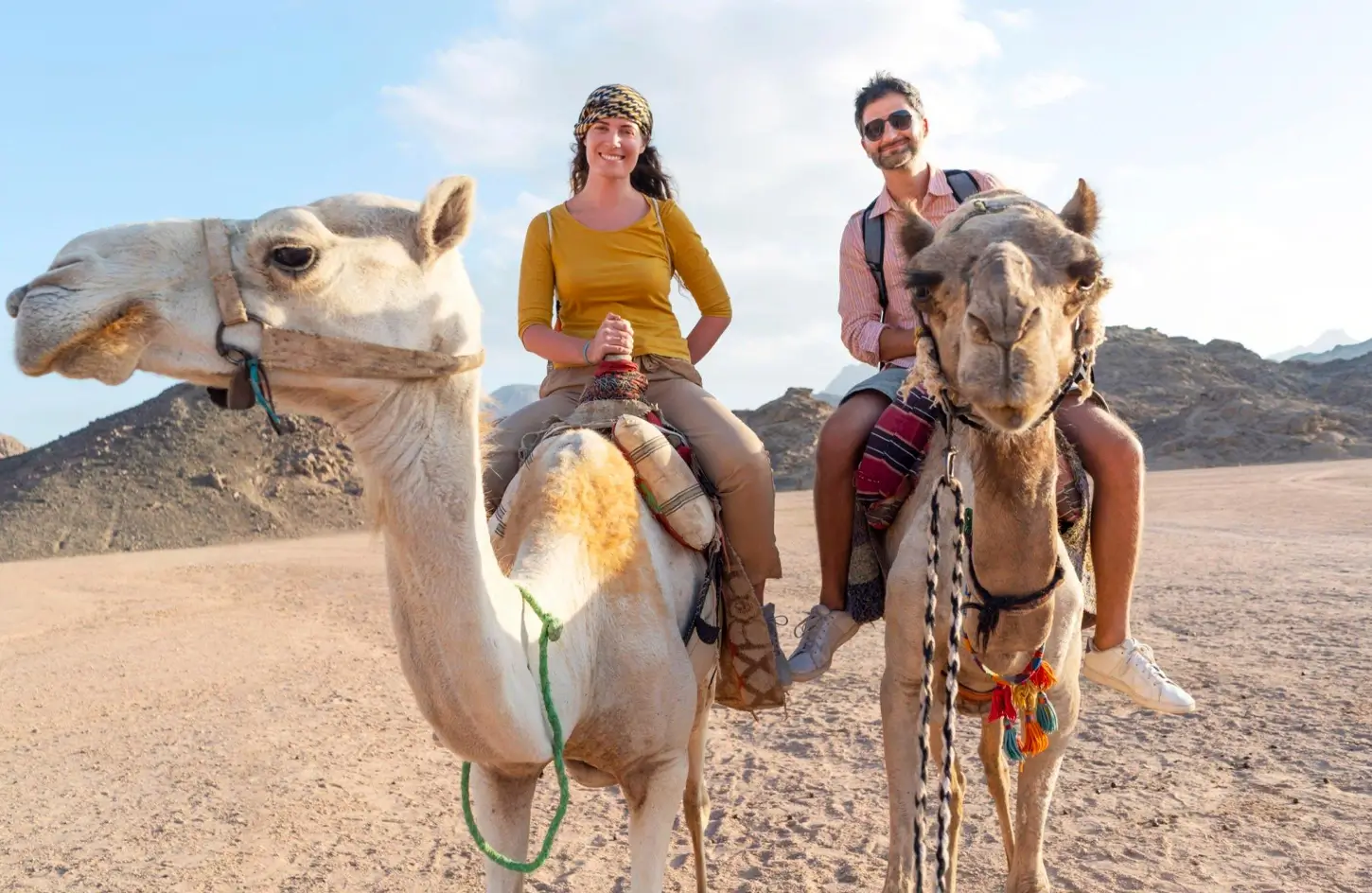 Couple riding camels on a desert safari